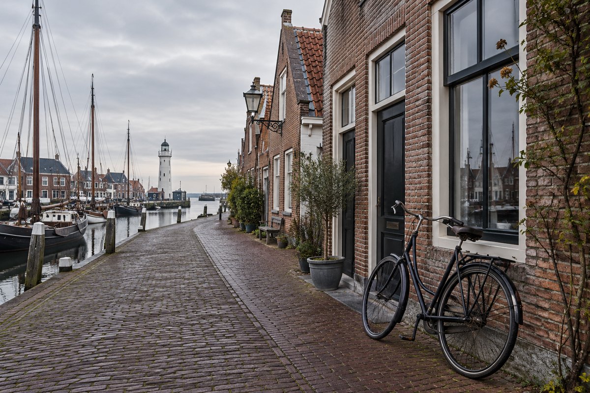 Stille bakstenen straat in een Friese havenstad, fiets zonder merk tegen een gevel, bewolkt, zonder mensen